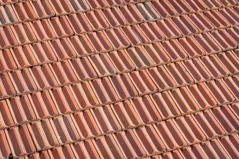 High-resolution image of overlapping clay roof tiles displaying a classic rustic pattern.