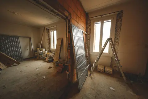 Interior view of a room under renovation with construction materials and a ladder.