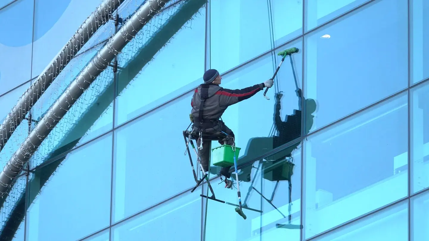 Window cleaner works on a high-rise glass building, ensuring spotless results.