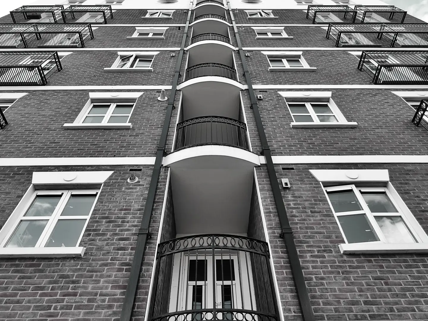 Low angle view of a modern brick building facade featuring multiple windows and glass balconies.