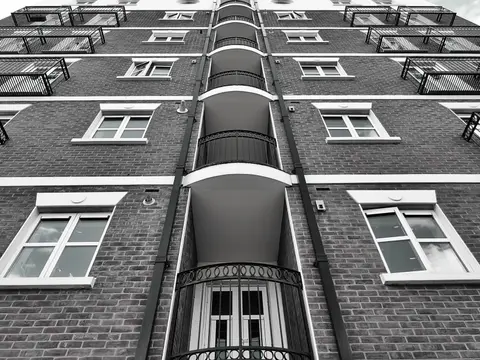 Low angle view of a modern brick building facade featuring multiple windows and glass balconies.