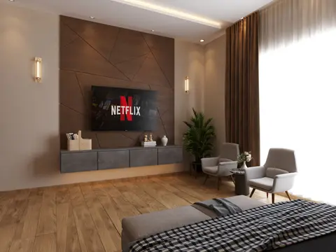A stylish living room featuring a flat screen TV, elegant decor, wooden flooring, and natural light.