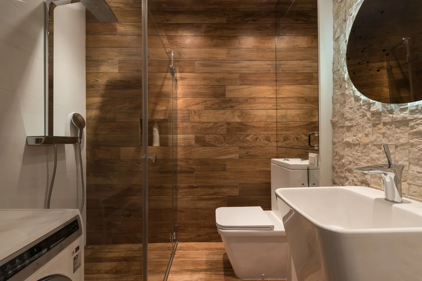 Stylish modern bathroom interior design with glass shower enclosure toilet bowl and sink under oval mirror