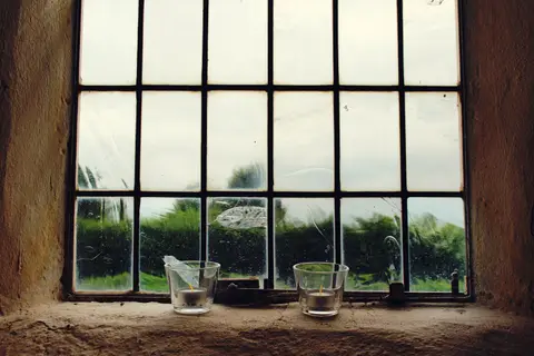 A rustic window with candles overlooking a serene landscape. Ideal for decoration themes.