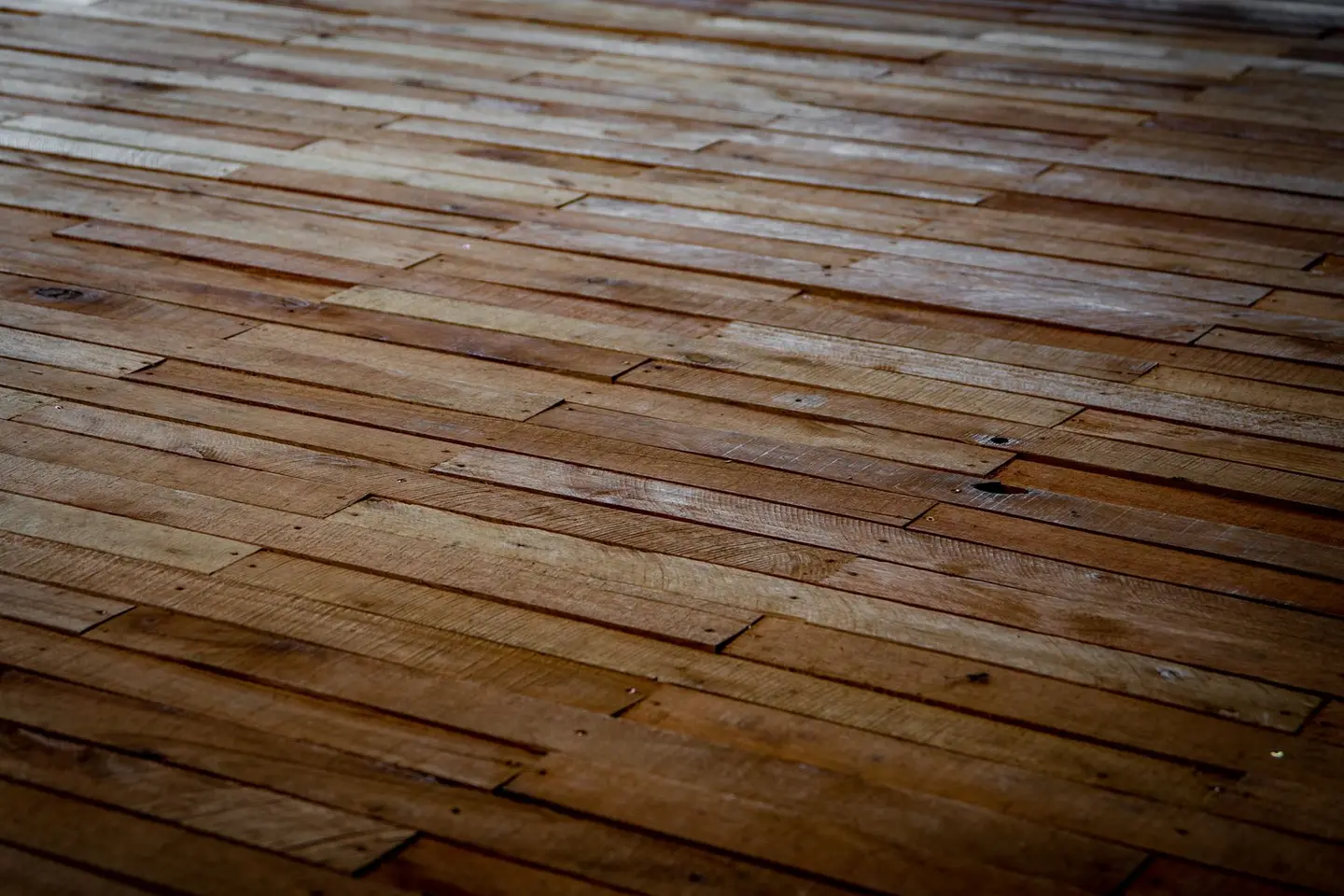 Detailed view of rustic wooden floor with staggered planks showcasing natural texture.