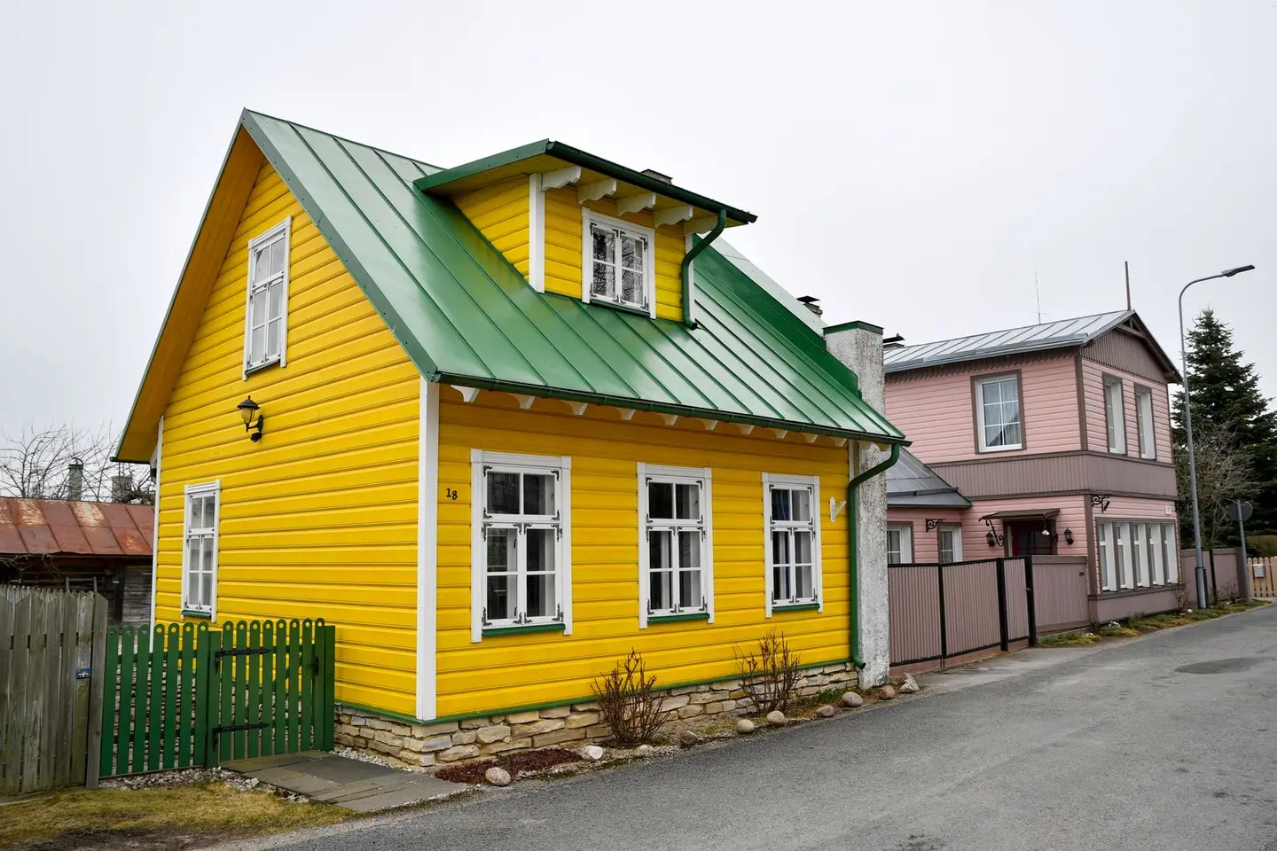 Beautiful yellow wooden house with green roof in a picturesque Estonian neighborhood.